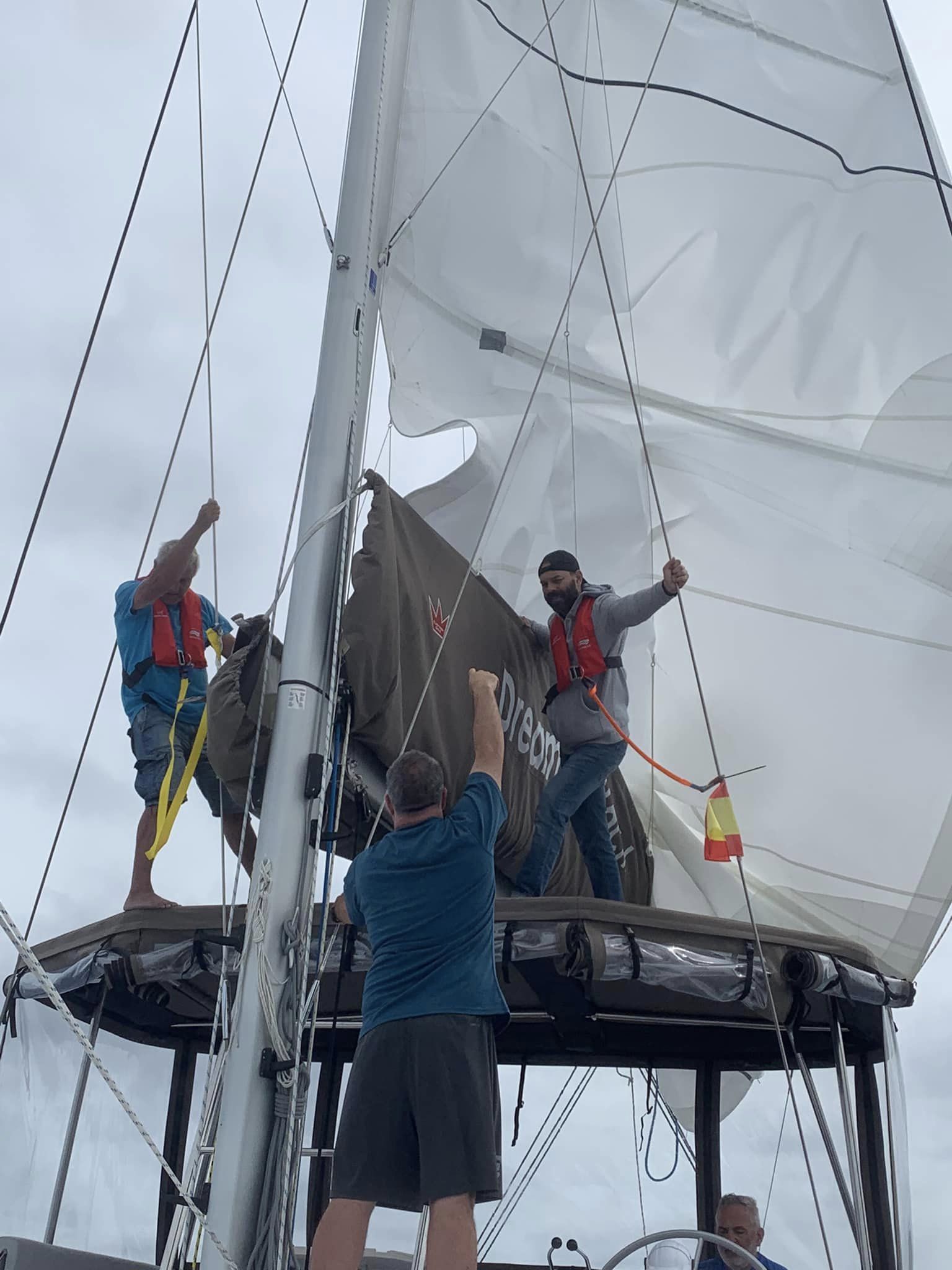 L’équipage répare la grand-voile sur le toit du catamaran, en pleine mer.
